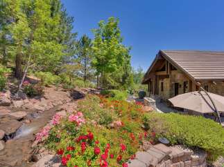 Experience the beauty of this stunning property, featuring a charming stone-accented home nestled amidst lush greenery and vibrant floral gardens.