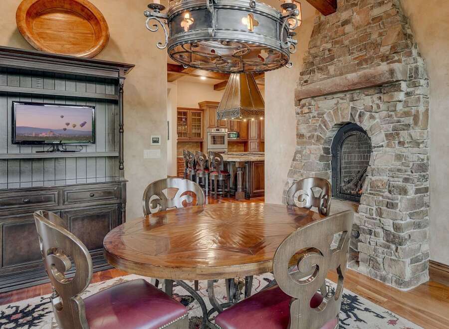 Experience rustic elegance in this dining area, featuring a grand stone fireplace and a polished wooden table perfect for gatherings.