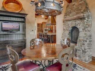 Experience rustic elegance in this dining area, featuring a grand stone fireplace and a polished wooden table perfect for gatherings.