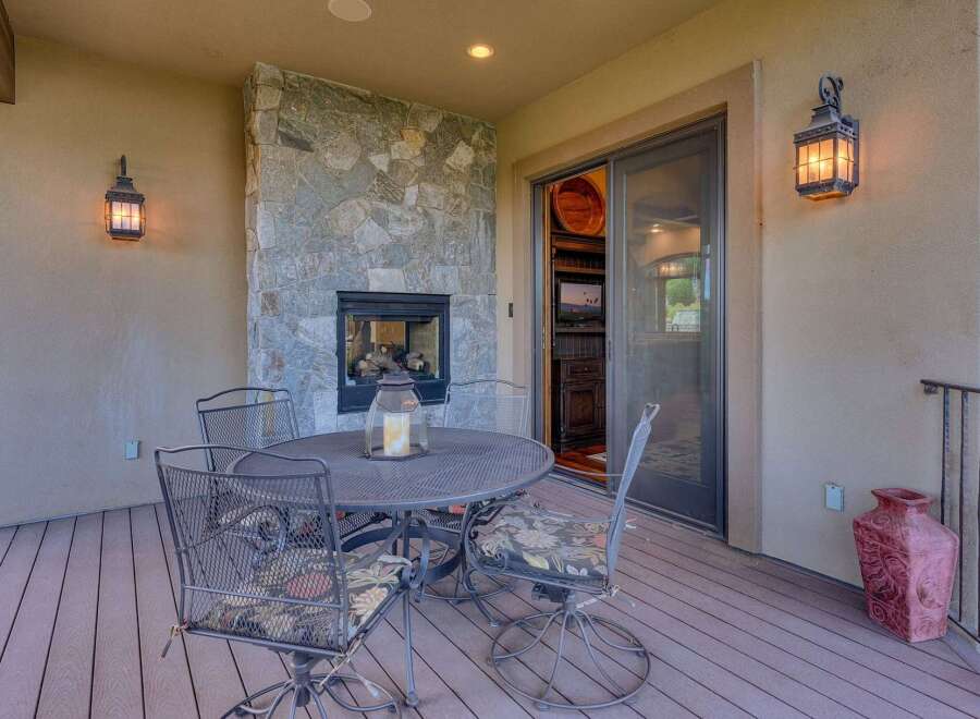 Enjoy outdoor living with this charming patio featuring a cozy stone fireplace and a dining set perfect for al fresco meals.