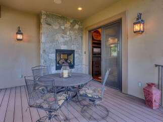 Enjoy outdoor living with this charming patio featuring a cozy stone fireplace and a dining set perfect for al fresco meals.