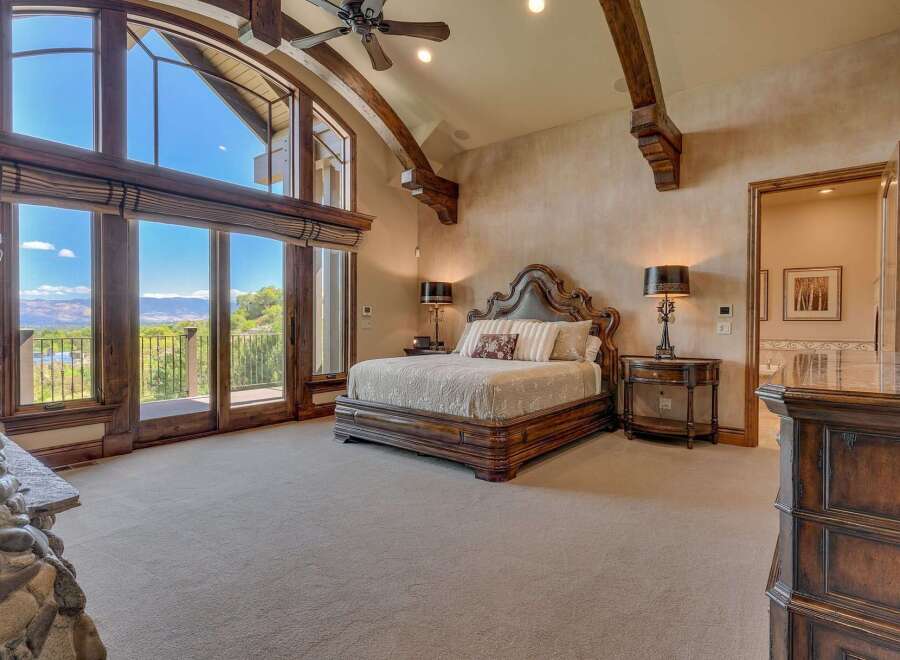 Experience luxury living in this master suite, featuring a grand wooden bed and a stunning stone fireplace.