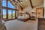 Experience luxury living in this master suite, featuring a grand wooden bed and a stunning stone fireplace.