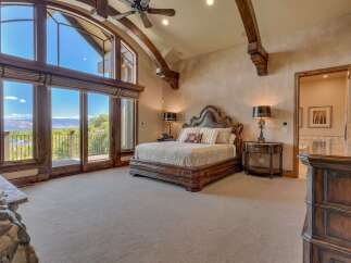 Experience luxury living in this master suite, featuring a grand wooden bed and a stunning stone fireplace.
