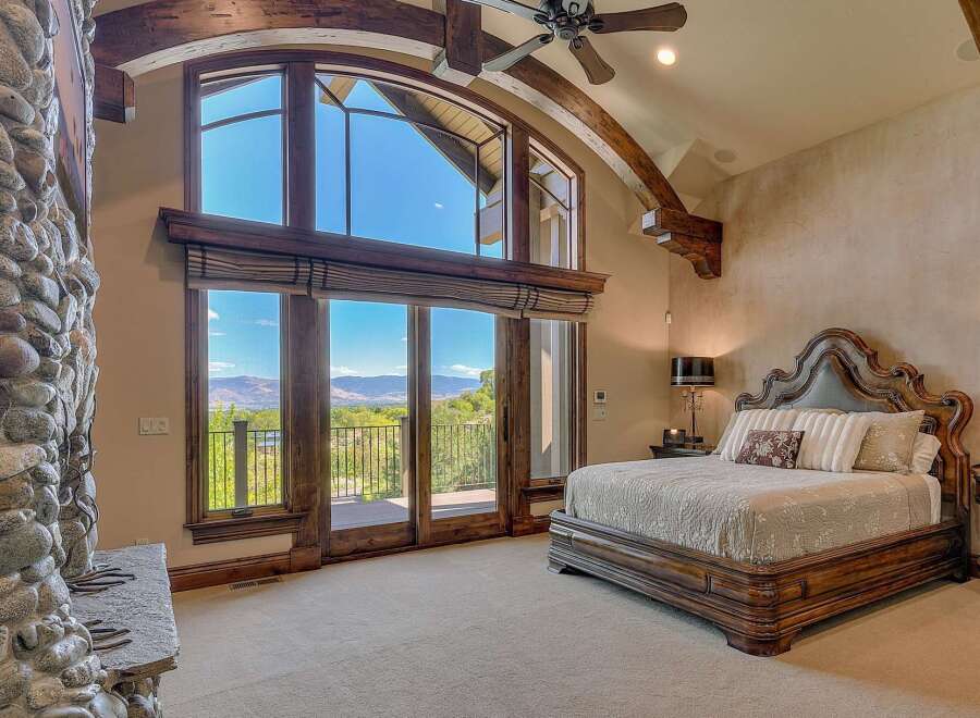 Experience luxury living in this stunning master bedroom, featuring a grand fireplace and expansive windows that offer breathtaking mountain views.