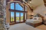 Experience luxury living in this stunning master bedroom, featuring a grand fireplace and expansive windows that offer breathtaking mountain views.