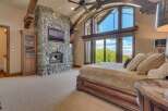 Experience luxury living in this master suite, featuring a grand stone fireplace and a mounted television for ultimate relaxation.