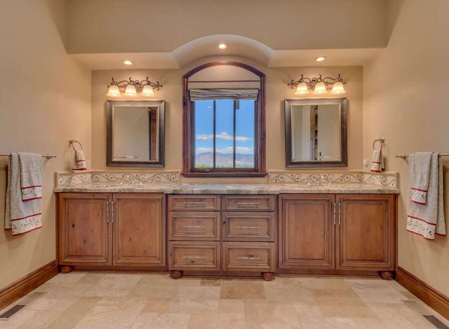 This luxurious bathroom features a double vanity with granite countertops and custom wood cabinetry, perfect for ample storage.