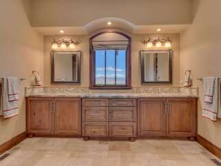 This luxurious bathroom features a double vanity with granite countertops and custom wood cabinetry, perfect for ample storage.