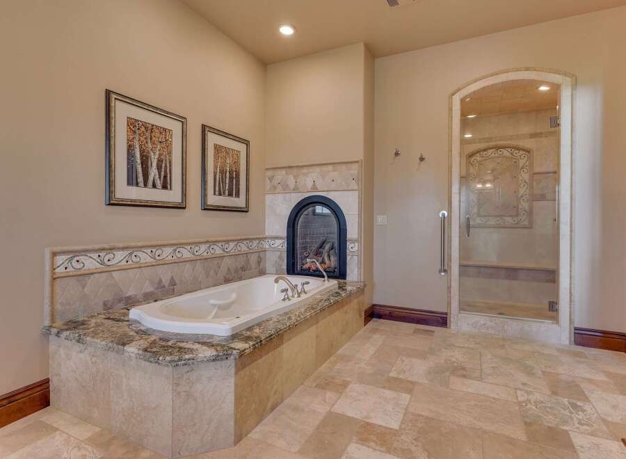 Indulge in luxury with this stunning bathroom featuring a deep soaking tub and a cozy fireplace, perfect for relaxation.