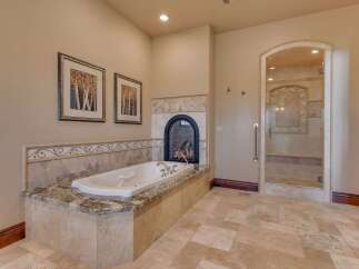 Indulge in luxury with this stunning bathroom featuring a deep soaking tub and a cozy fireplace, perfect for relaxation.