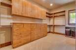 This spacious walk-in closet features ample storage with custom wooden cabinetry, including a long dresser with numerous drawers and overhead cabinets.