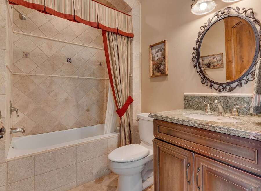 This charming bathroom features a classic clawfoot tub with a decorative tiled surround and a matching shower curtain.