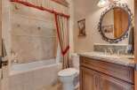 This charming bathroom features a classic clawfoot tub with a decorative tiled surround and a matching shower curtain.