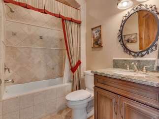 This charming bathroom features a classic clawfoot tub with a decorative tiled surround and a matching shower curtain.