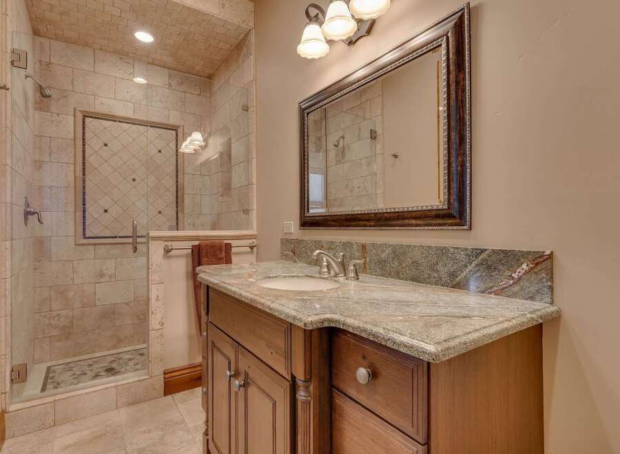 Indulge in luxury with this beautifully appointed bathroom featuring a spacious walk-in shower with intricate tile work and a rainfall showerhead.