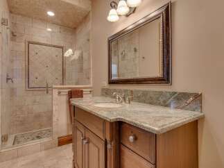 Indulge in luxury with this beautifully appointed bathroom featuring a spacious walk-in shower with intricate tile work and a rainfall showerhead.