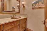 Experience rustic elegance in this powder room, featuring a custom wood vanity with ornate hardware and a hammered copper sink.