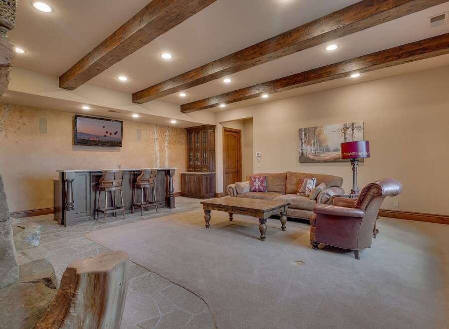 This rustic basement living area features a full-service bar with ample seating, perfect for entertaining guests.