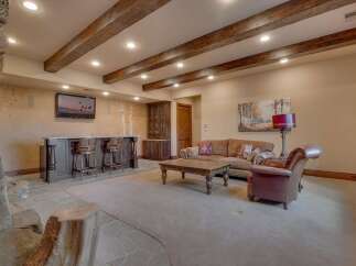 This rustic basement living area features a full-service bar with ample seating, perfect for entertaining guests.