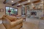 Experience rustic elegance in this living room, featuring a grand stone fireplace with a natural wood mantel and a roaring fire.