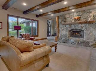 Experience rustic elegance in this living room, featuring a grand stone fireplace with a natural wood mantel and a roaring fire.