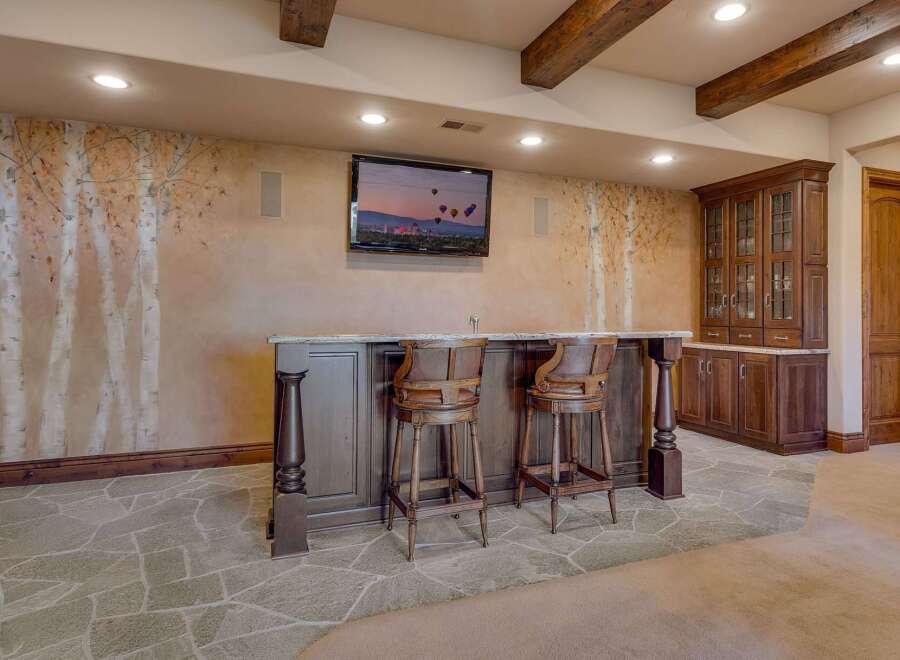 This stunning basement features a custom-built bar area with elegant wooden stools, perfect for entertaining guests.