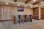 This stunning basement features a custom-built bar area with elegant wooden stools, perfect for entertaining guests.