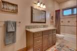 This charming bathroom features a spacious vanity with a granite countertop and ample storage, complemented by a large mirror and elegant lighting.