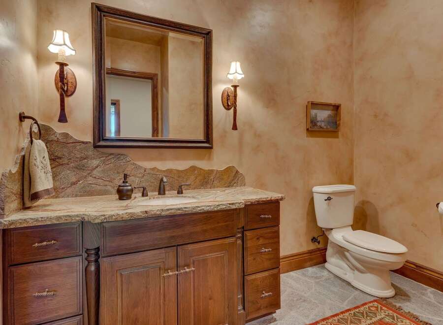 This rustic bathroom features a custom wood vanity with a granite countertop and a unique backsplash.