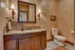This rustic bathroom features a custom wood vanity with a granite countertop and a unique backsplash.