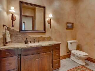 This rustic bathroom features a custom wood vanity with a granite countertop and a unique backsplash.