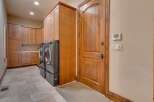 This spacious laundry room features ample storage with custom wooden cabinetry and a convenient side-by-side washer and dryer setup.