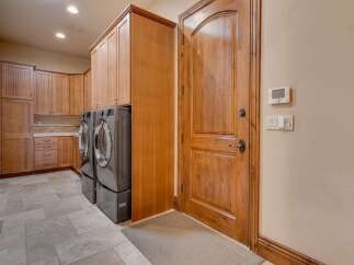 This spacious laundry room features ample storage with custom wooden cabinetry and a convenient side-by-side washer and dryer setup.