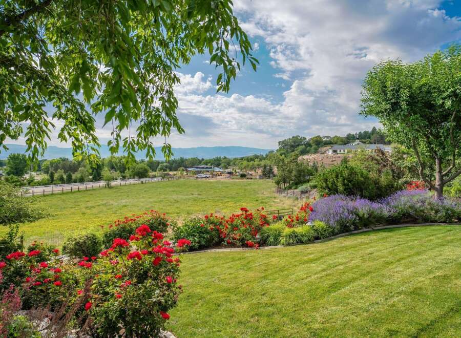 Experience the beauty of this expansive property, featuring vibrant red roses and calming lavender bushes that lead to a lush green lawn.