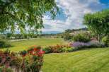 Experience the beauty of this expansive property, featuring vibrant red roses and calming lavender bushes that lead to a lush green lawn.