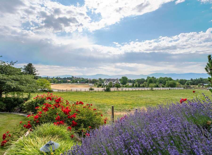 Experience serene country living with this stunning property, boasting vibrant red roses and fragrant lavender in the foreground.