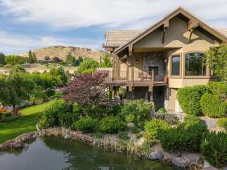 Experience luxury living in this stunning home, featuring a multi-level deck overlooking a serene pond and lush landscaping.