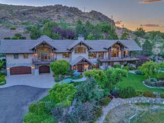 Experience luxury living in this stunning mountain estate, featuring a grand entrance, expansive windows, and multiple balconies offering breathtaking views.