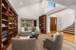 Step into this inviting living room featuring soaring vaulted ceilings and a wall of custom built-in bookshelves, perfect for the avid reader.