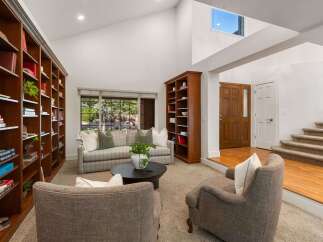 Step into this inviting living room featuring soaring vaulted ceilings and a wall of custom built-in bookshelves, perfect for the avid reader.