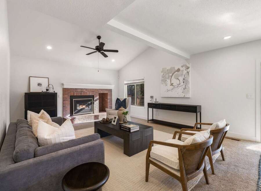 Experience modern living in this spacious living room, featuring a striking brick fireplace and vaulted ceilings with exposed beams.