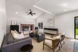 Experience modern living in this spacious living room, featuring a striking brick fireplace and vaulted ceilings with exposed beams.