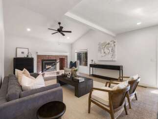 Experience modern living in this spacious living room, featuring a striking brick fireplace and vaulted ceilings with exposed beams.