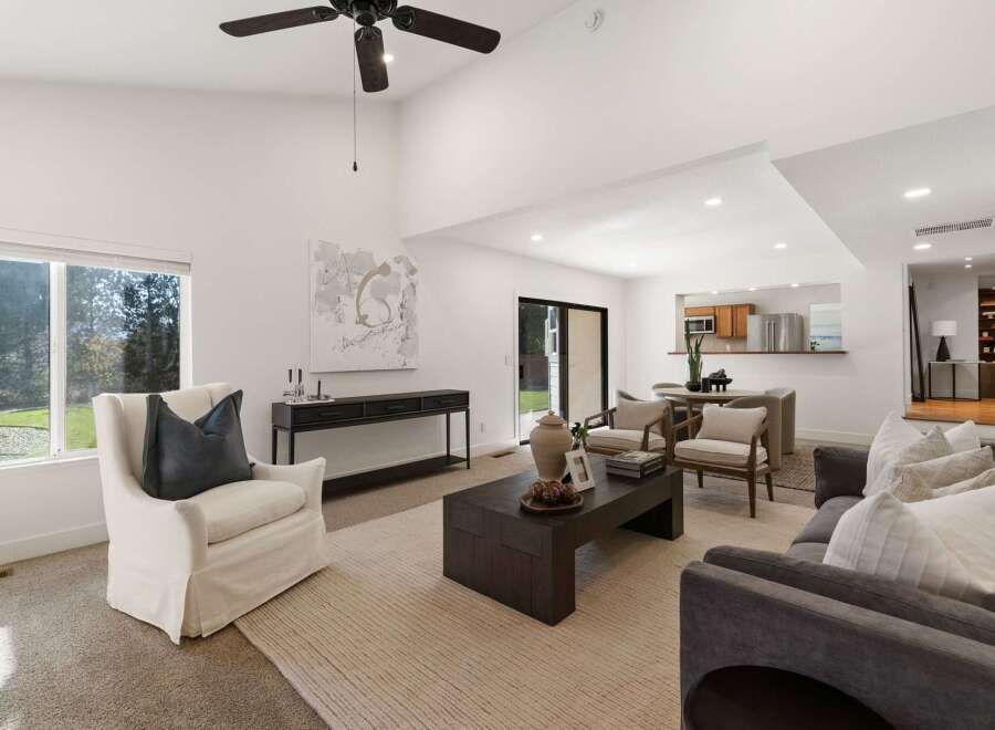 Experience modern living in this spacious open-concept living area, featuring a vaulted ceiling and abundant natural light from large windows.