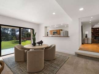 Enjoy a bright and airy dining space with a large sliding glass door that opens to a lush green backyard.