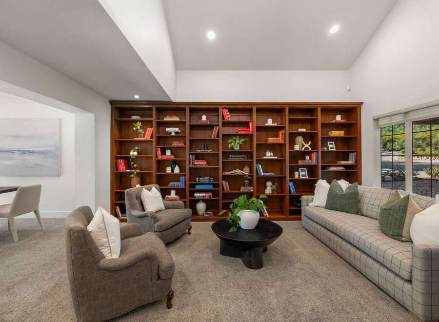 Step into this inviting living room, featuring a grand floor-to-ceiling bookshelf perfect for displaying your literary collection.