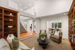 This spacious living room boasts a grand two-story layout with a prominent wooden staircase leading to the upper level.