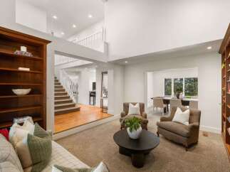 This spacious living room boasts a grand two-story layout with a prominent wooden staircase leading to the upper level.