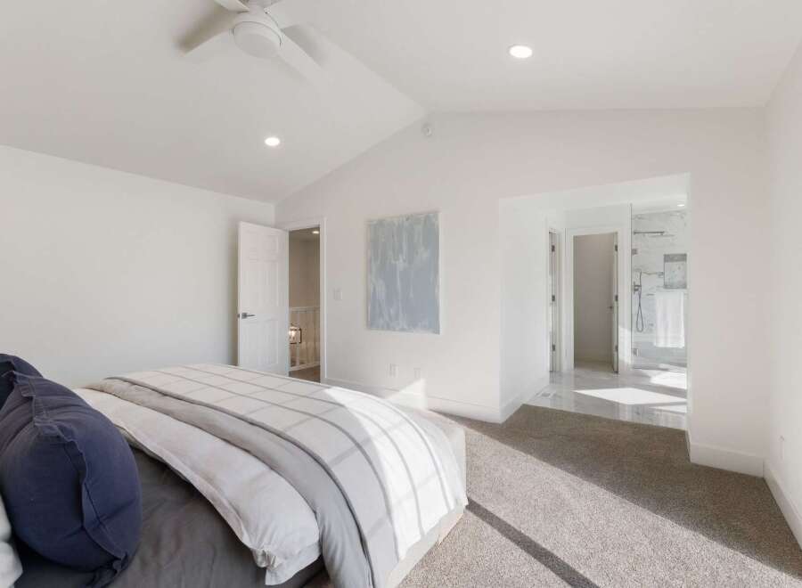 Experience modern luxury in this spacious bedroom featuring a vaulted ceiling and a sleek ceiling fan.